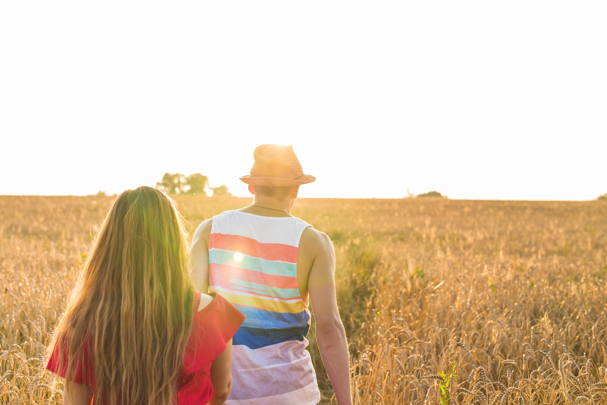 Young love couple walking on field in sunlight